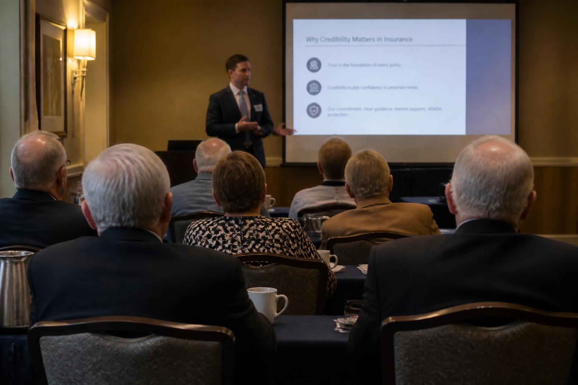 An insurance professional presenting at a small educational seminar